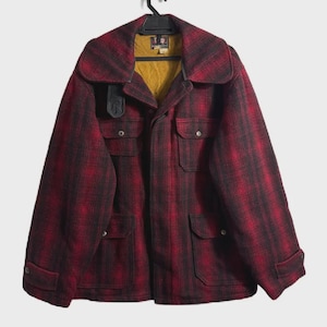 May include: A red and black plaid wool coat with a large collar and multiple pockets. The coat is hanging on a black hanger. The interior lining is yellow.
