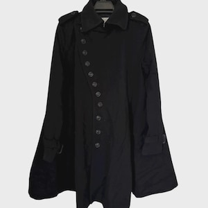 May include: A black trench coat with a double-breasted design, featuring a series of buttons down the front. The coat has a classic collar, shoulder epaulets, and long sleeves with cuff details. It hangs on a black hanger against a neutral background.