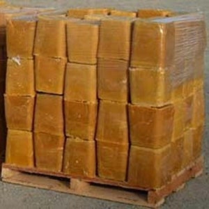 May include: A pallet of stacked, rectangular blocks of amber-colored material, wrapped in clear plastic. The blocks are uniform in size and shape, suggesting a manufactured product. The pallet is made of wood.
