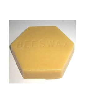 May include: A hexagonal block of beeswax, with the word "BEESWAX" embossed on the surface. The wax is a light yellow color. The product is likely used for crafting or cosmetic purposes.