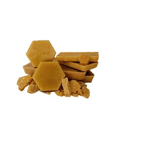 May include: A collection of golden-yellow beeswax blocks and fragments. The blocks are in various shapes, including hexagonal and rectangular forms. The word "BEESWAX" is imprinted on some of the blocks. The image is set against a white background.