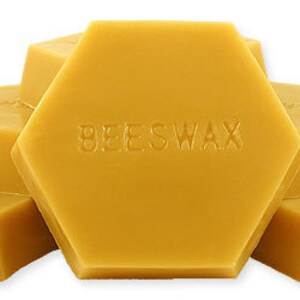 May include: Hexagonal blocks of yellow beeswax, stacked to show the product. The word "BEESWAX" is embossed on the central block. The blocks have a smooth, solid appearance, suggesting a natural product.