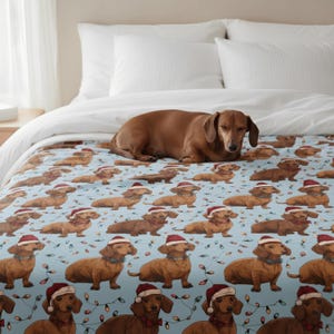 May include: A light blue blanket featuring a repeating pattern of dachshunds wearing Santa hats and string lights. A brown dachshund dog is lying on top of the blanket. The blanket is on a bed with white pillows.