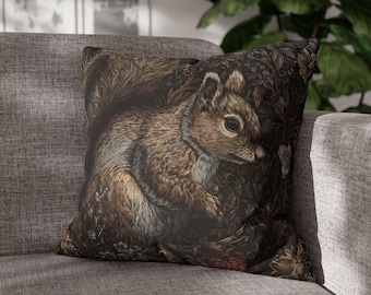 Könnte beinhalten: Quadratisches Kissen mit einer detaillierten Illustration eines Eichhörnchens in einer Waldszene. Das Design hat einen dunklen Hintergrund mit braunen, beigen und grauen Farbtönen. Das Eichhörnchen ist das zentrale Element, das ein Vintage- und Naturgefühl vermittelt.