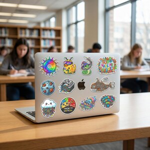 May include: A silver laptop covered in colorful stickers. The stickers feature various designs, including a rainbow sun, a duck, a snake, a cloud, and the words "PRIORITY CRITICAL". The laptop is on a wooden desk in a library.