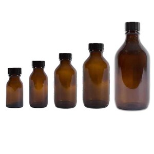 May include: Five amber glass bottles with black caps, displayed in a row. The bottles vary in size, demonstrating different capacities. The glass has a warm, brown colour, and the caps are solid black.