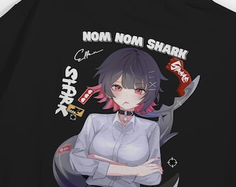 May include: A black t-shirt featuring a graphic print of an anime-style character with dark hair and red eyes, wearing a white collared shirt and a black choker. The text "NOM NOM SHARK" appears above the character, surrounded by various small icons.