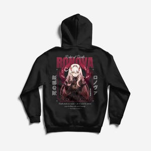 Puede incluir: Una sudadera negra con capucha que presenta un gráfico en la espalda de un personaje estilo anime con cabello largo claro, armadura oscura y motivos de ojos rojos. El texto dice Ruler of Death, RONOVA, e incluye caracteres japoneses y la cita Death abides no reason.