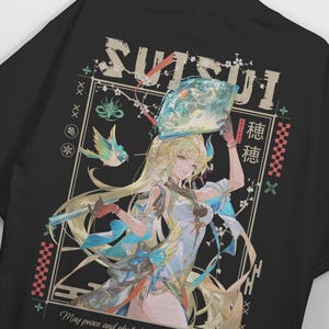 Może przedstawiać: Czarny t-shirt z grafiką przedstawiającą blond postać w jasnym stroju, trzymającą wachlarz nad głową. Wzór zawiera napis SUISUI, japońskie znaki, ptaka, gałązki kwiatowe oraz frazę May peace and play.