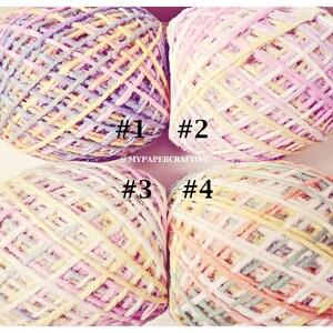 Könnte beinhalten: Vier Knäuel Garn in verschiedenen Schattierungen von Rosa, Gelb und Blau. Das Garn ist quadratisch angeordnet, wobei jedes Knäuel mit einer Nummer von 1 bis 4 gekennzeichnet ist.