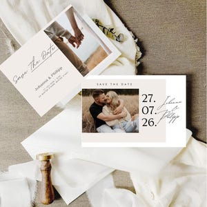 以下が含まれることがあります： 結婚式の招待状セット。写真付きの「Save the Date」カードが含まれています。カードは薄いベージュ色で、黒い文字が書かれています。木製のワックスシールと白いリボンもあり、素朴なテーマを示唆しています。