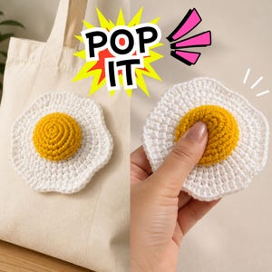 Puede incluir: Un parche de ganchillo con forma de huevo frito con borde blanco y centro amarillo elevado, sujeto a una bolsa de tela beige y sostenido en una mano. La imagen presenta un gráfico de estrella amarillo y rojo con el texto negro POP IT.