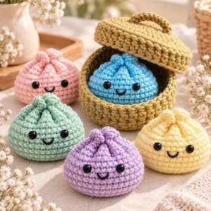 Puede incluir: Un conjunto de cinco peluches de ganchillo con forma de empanadillas, cada uno con ojos de cuentas negras y una sonrisa bordada. El set incluye piezas en rosa claro, verde menta, morado claro, amarillo pálido y una azul dentro de una cesta.
