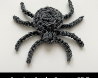 May include: A dark gray crocheted spider applique featuring a circular body and eight segmented legs. The yarn texture is visible throughout the piece, which is displayed against a plain white background. The text Crochet Spider Pattern PDF is visible.