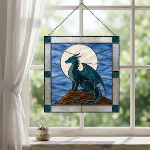 Peut inclure: Un panneau décoratif carré en vitrail suspendu représentant un dragon sarcelle perché sur un rocher brun devant une grande lune blanche circulaire. Le fond est composé de panneaux de verre bleu ondulé, encadrés par une bordure en verre clair.