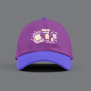 May include: A purple baseball cap with a blue brim. The cap features the text "SNACK LEARN REPEAT!" above a graphic of a sandwich, a bag of chips, and a book. The cap is a casual accessory.
