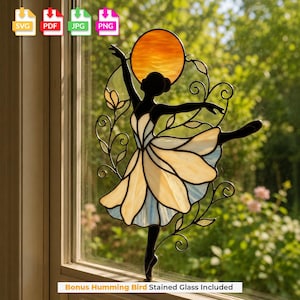 May include: A stained glass suncatcher featuring a black silhouette of a dancer with a flowing skirt made of cream and light blue glass panels. Above the dancer is a circular orange glass sun, surrounded by black wire vines and floral accents.