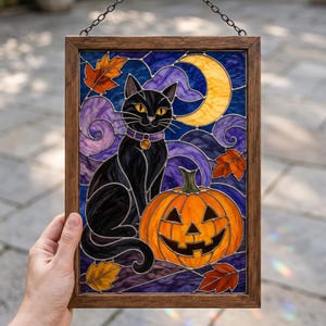 May include: A rectangular stained glass panel in a wooden frame featuring a black cat with yellow eyes and a purple collar sitting next to an orange jack-o'-lantern. The background displays a yellow crescent moon, purple swirls, and orange autumn leaves.