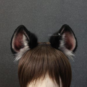 May include: A pair of black and gray faux fur cat ears attached to a headband. The inner ear is a dark burgundy color. The ears are attached to a brown wig. The text "ElifeEhappy.etsy.com" is visible.
