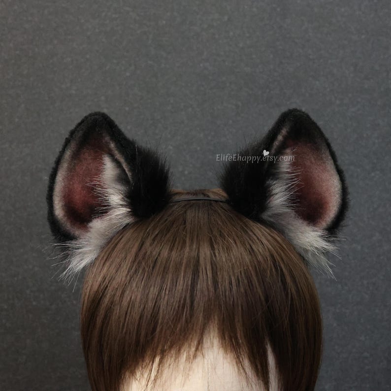 May include: A pair of black and gray faux fur cat ears attached to a headband. The inner ear is a dark burgundy color. The ears are attached to a brown wig. The text "ElifeEhappy.etsy.com" is visible.