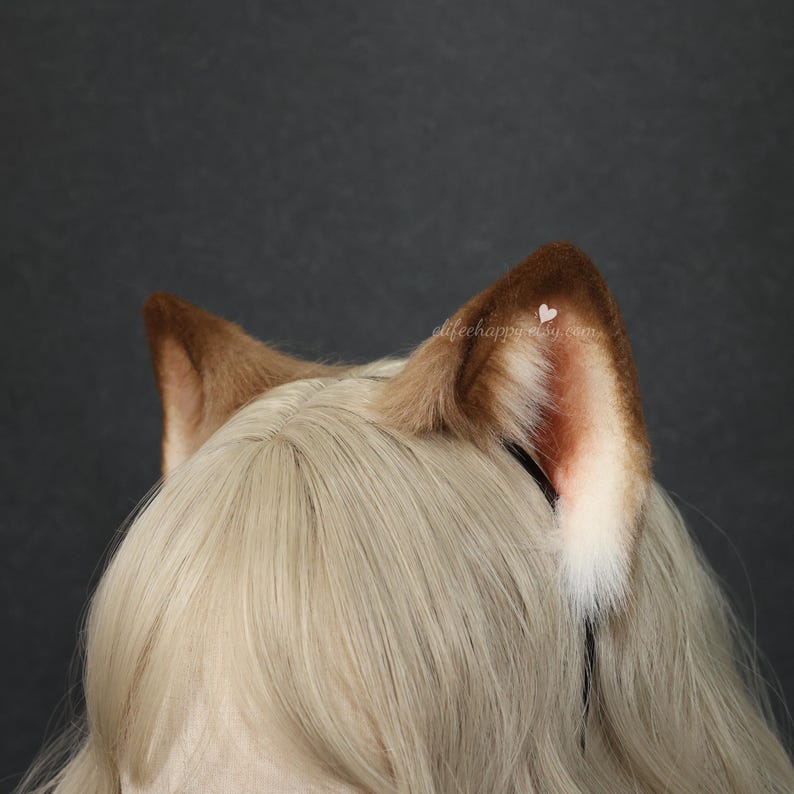 May include: A pair of faux fur animal ears in shades of brown, tan, and white, attached to a thin black headband. The ears feature a dark brown outer edge that transitions into a lighter tan and white interior. The text elifehappy.etsy.com is visible.