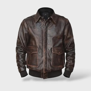 Könnte beinhalten: Braune Lederjacke mit klassischem Design. Mit Kragen, zwei Vordertaschen und gerippten Bündchen und Saum. Die Jacke hat einen Vintage-Look mit Used-Effekt.