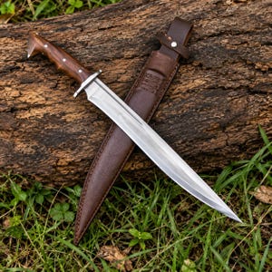 Puede incluir: Un cuchillo de hoja fija con una hoja de acero pulido y un mango de madera marrón oscuro contorneado con tres remaches plateados. El cuchillo viene acompañado de una funda de cuero marrón a juego con correa de cierre y costuras.