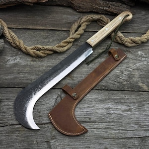 Könnte beinhalten: Eine große Machete mit gebogener Klinge, hellem Holzgriff und brauner Lederscheide. Die Klinge hat eine dunkle, strukturierte Oberfläche mit einer scharfen, silbernen Kante. Eine grüne Schnur ist am Griff befestigt. Die Machete ist etwa 46 cm lang.