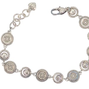 May include: Silver-toned bracelet featuring a series of circular, decorative links. Each link has a central design surrounded by a beaded border. The bracelet has a lobster clasp closure and an adjustable chain.