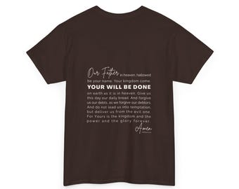 Puede incluir: Una camiseta marrón oscuro con el texto "Our Father" y la oración del Señor impresa en blanco. La camiseta es de cuello redondo y está hecha de un material suave.
