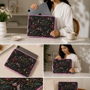 May include: Black tablet sleeve with a colorful floral pattern featuring pink, blue, and green accents. The sleeve has a pink and white striped border. The sleeve is designed to hold a tablet.