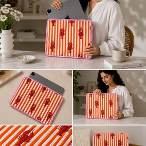 May include: A rectangular tablet sleeve featuring a repeating pattern of red lobsters on orange and white vertical stripes. The sleeve has a pink trim and is shown with a tablet inside. The overall theme is coastal and nautical.