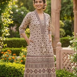 May include: A beige and brown patterned dress with a V-neckline, three-quarter sleeves, and pockets. The dress features a geometric design and a tassel tie. The model is wearing matching flats. The dress is knee-length and suitable for warm weather.