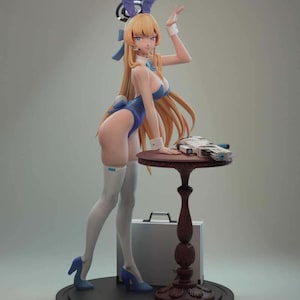 May include: A figurine of a woman in a blue bunny costume with long blonde hair, blue heels, and white thigh-high stockings. She is leaning on a small, round, brown table with a futuristic device on top. A briefcase is behind the table.
