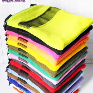 May include: A stack of colorful fleece pet beds in various colors, including yellow, pink, black, and blue. Each bed has a zippered opening and a mesh window. The beds are designed for small pets.