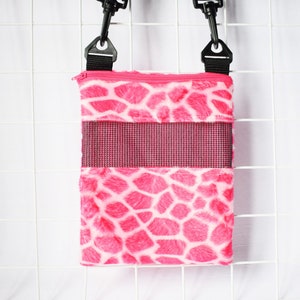 May include: A pink and white patterned pet carrier with a black adjustable strap. The carrier has a mesh window and a zip closure. The text "Pinoy Pet Cuddle Cup" is visible in the upper left corner.