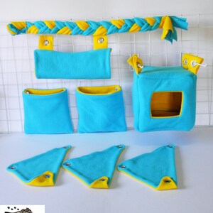 May include: A set of blue and yellow fleece pet cage accessories. The set includes a hanging hammock, a hanging pouch, a hanging cube, and three hanging triangles. The accessories are made of soft fleece and are perfect for small pets like hamsters, gerbils, and rats.
