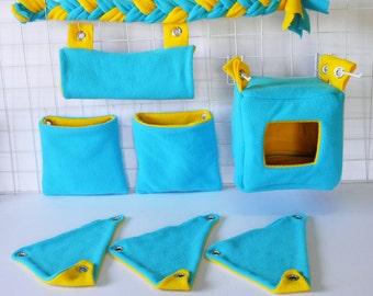 Puede incluir: Un conjunto de accesorios para jaulas de mascotas de felpa azul y amarilla. El conjunto incluye una hamaca colgante, una bolsa colgante, un cubo colgante y tres triángulos colgantes. Los accesorios están hechos de felpa suave y son perfectos para mascotas pequeñas como hámsters, jerbos y ratas.