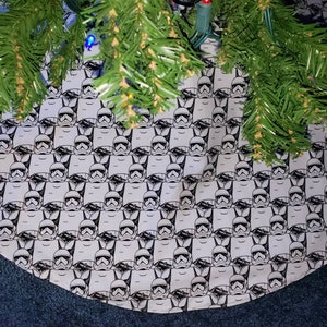 May include: A white and black Christmas tree skirt with a repeating pattern of Stormtrooper helmets from Star Wars.