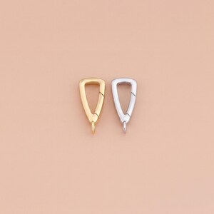 Puede incluir: Dos cierres para joyería con forma triangular, uno en tono dorado pulido y otro en tono plateado pulido. Cada cierre cuenta con una compuerta con resorte en un lado y una pequeña anilla fija en la parte inferior para unir componentes.