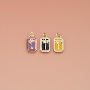 May include: Three gold-colored pendants with a rectangular shape and a palm tree design. Each pendant has a different background color: purple, black, and yellow. The pendants are connected to a small gold loop.