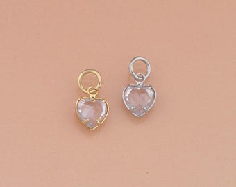 Puede incluir: Dos colgantes en forma de corazón. Uno tiene un engaste dorado y una piedra clara en forma de corazón facetado. El otro tiene un engaste plateado y una piedra clara en forma de corazón facetado. Ambos tienen un pequeño lazo en la parte superior.