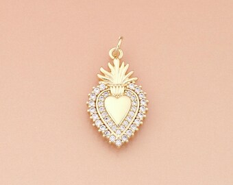 May include: Gold-colored heart pendant with a halo of small, clear crystals. The pendant has a heart-shaped center and a crown-like design at the top. The pendant is suspended from a small loop.