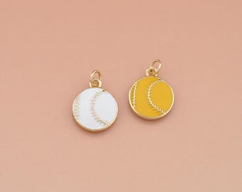 Pode incluir: Dois pingentes redondos com bordas e laços dourados. Um é branco com costuras douradas, assemelhando-se a uma bola de beisebol. O outro é amarelo com costuras douradas, também se assemelhando a uma bola de beisebol. O fundo é de cor pêssego claro.