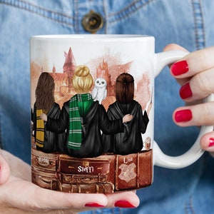 Könnte beinhalten: Weiße Keramiktasse mit einer bunten Illustration von drei Freunden in Zaubererroben, die vor einem Schloss stehen. Die Tasse trägt die Namen "Kedi", "Steffi" und "Lisa".