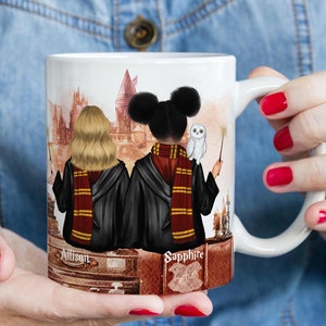 May include: White ceramic mug featuring a custom illustration of two figures in Hogwarts robes, with a castle backdrop. One figure has blonde hair, the other has black hair. The mug includes the names "Allison" and "Sapphire".