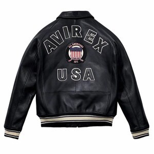 Op de afbeelding: Zwarte leren jas met wit geborduurde "AVIREX" en "USA" letters. Voorzien van een patch met de Amerikaanse vlag en de woorden "ALL AMERICANS ESTABLISHED 1975". De jas heeft een geribbelde kraag, manchetten en zoom met witte en zwarte strepen.