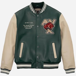 May include: A green and beige varsity jacket with the text "AVIREX USA" and "The King of Aviation Classic Varsity B.I.S.O.N.S." The jacket features a patch with a bison graphic and the letters "AX". The jacket has a striped collar, cuffs, and hem.