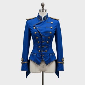 Può includere: Giacca blu reale in stile militare con bottoni e finiture dorate. La giacca presenta un colletto alto, spalline e una silhouette aderente. Abbellimenti dorati adornano i polsini e le tasche, offrendo un aspetto formale ed elegante.