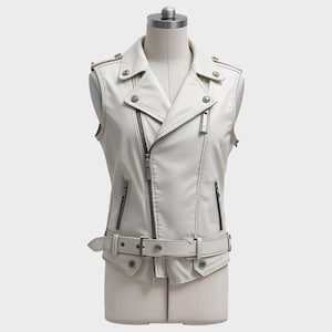 May include: A sleeveless white leather jacket with a classic biker style. Features include a notched lapel, asymmetrical zipper closure, multiple zippered pockets, and a belt at the waist. The jacket is displayed on a mannequin.